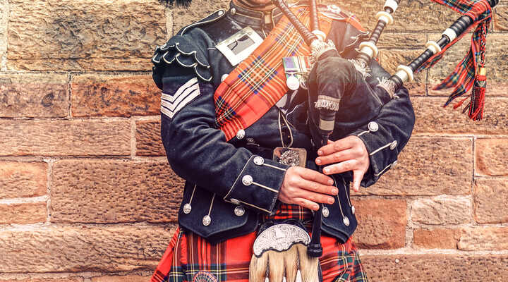 A super close up of a man wearing tartan and playing the bagpipes